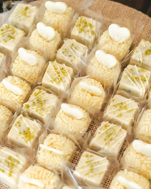 Doces finos de chocolate branco embalados, finalizados com pistache e coraçõezinhos