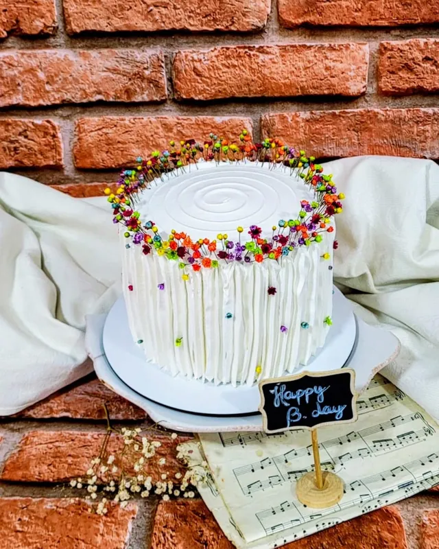 Bolo branco texturizado com coroa de flores secas coloridas no topo