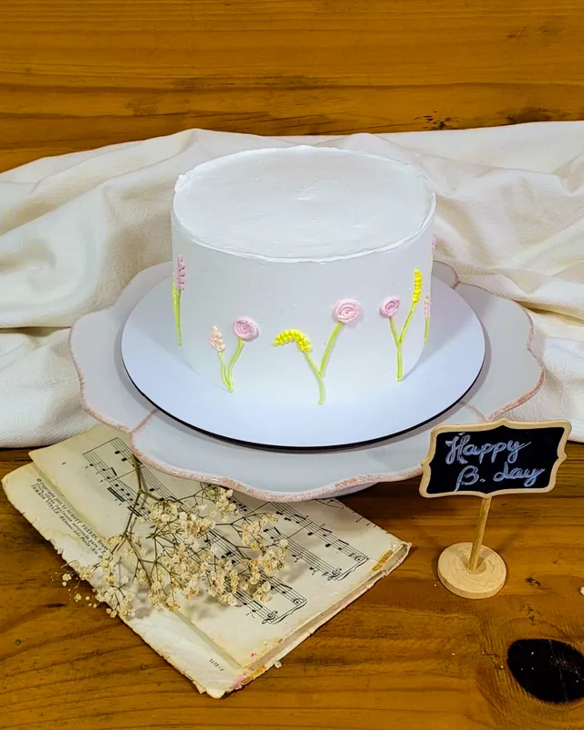 Bolo branco com florzinhas pintadas à mão em rosa e amarelo na lateral