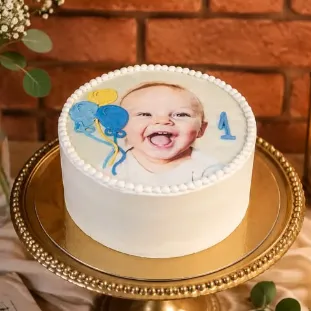 Bolo branco com foto comestível de bebê e balões, em boleira dourada